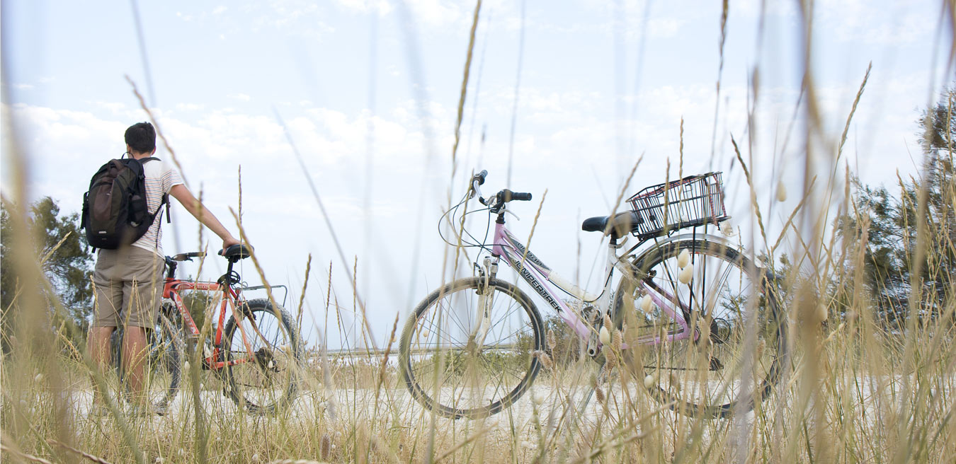 Ein Mann mit Fahrrad und ein einzeln abgestelltes Fahrrad in einer Küstenlandschaft
